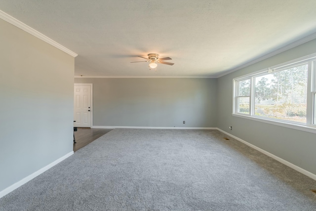 empty room with ceiling fan, dark carpet, and crown molding