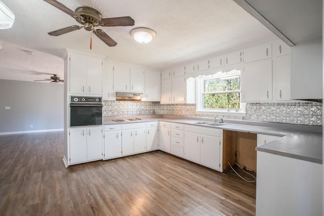 kitchen with white cabinets, sink, light wood-type flooring, a textured ceiling, and black oven
