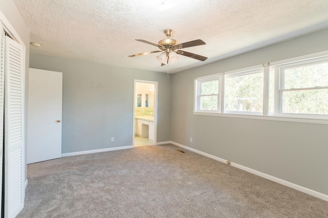 unfurnished bedroom with connected bathroom, ceiling fan, a textured ceiling, light carpet, and a closet