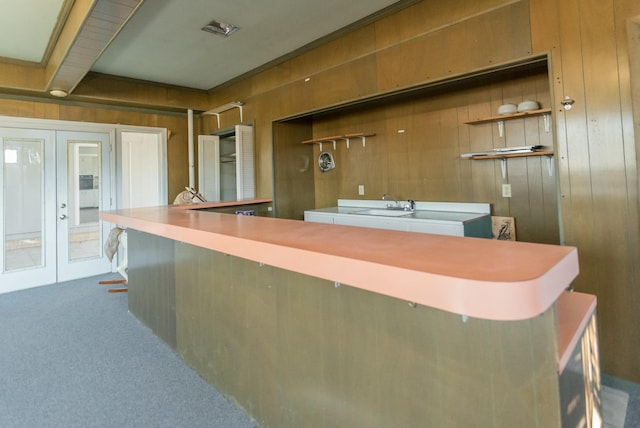 interior space featuring sink, french doors, carpet floors, and wood walls
