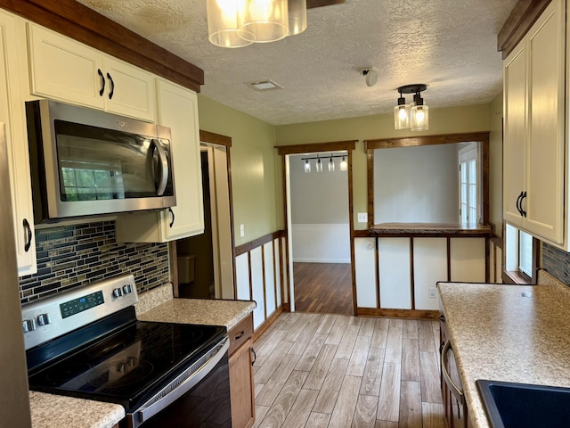 3777 Pine Ridge Run, Martinez, GA 30907 - kitchen featuring stainless steel appliances, light wood-style floors, white cabinetry, light countertops, and a textured ceiling