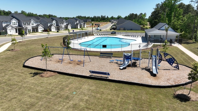 community pool featuring playground community, a residential view, and a lawn