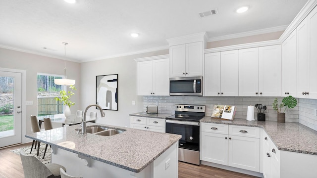 kitchen featuring a sink, crown molding, wood finished floors, and stainless steel appliances