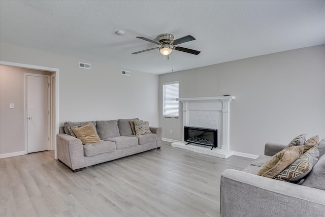 2904 Pleasant Ct, Augusta, GA 30907 - living room featuring light wood-style flooring, a ceiling fan, a fireplace, and a textured ceiling