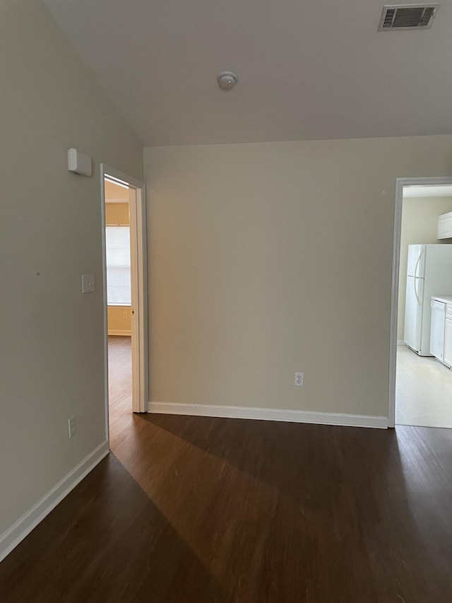 spare room featuring baseboards, visible vents, and wood finished floors
