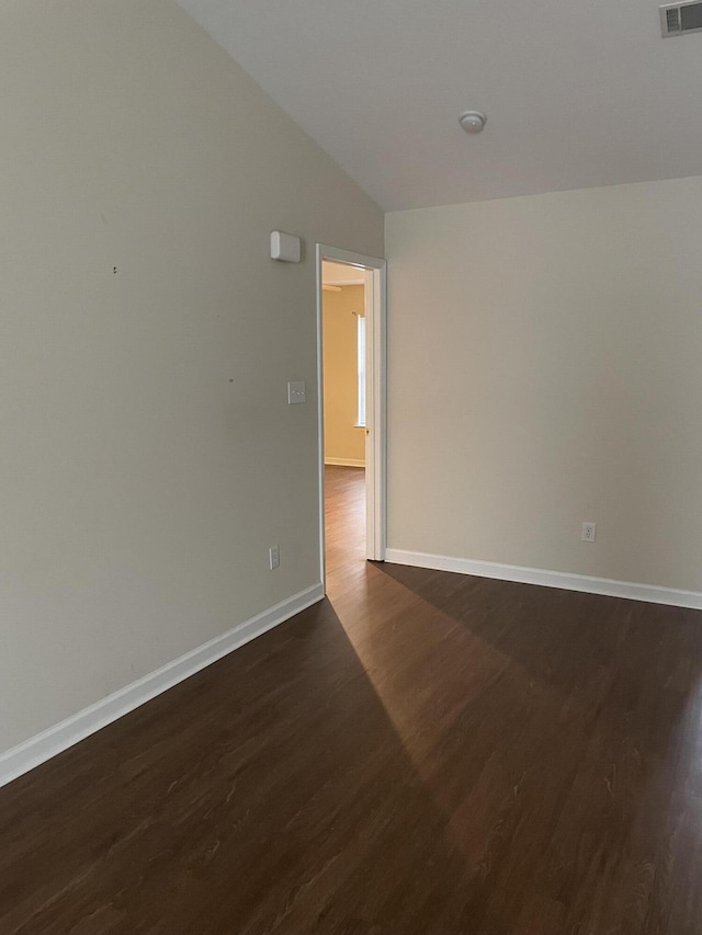 empty room featuring dark hardwood / wood-style flooring and vaulted ceiling