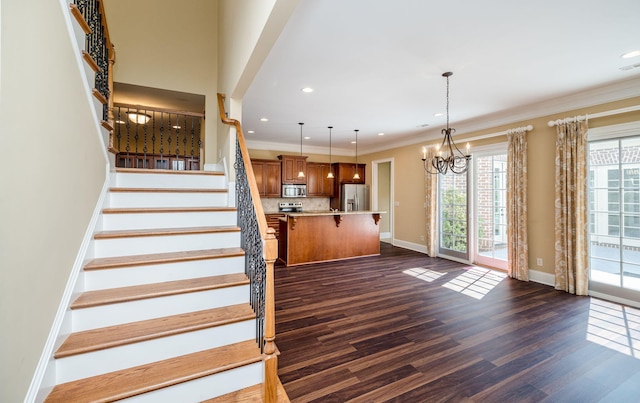 staircase with hardwood / wood-style floors, crown molding, and a chandelier