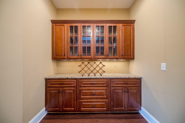 bar with light stone counters and dark wood-type flooring