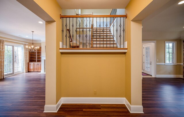 hallway with built in features, an inviting chandelier, and dark wood-type flooring