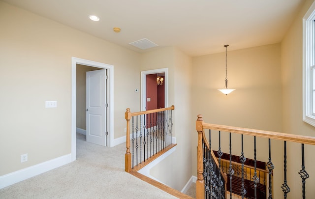 hall with a chandelier and light colored carpet