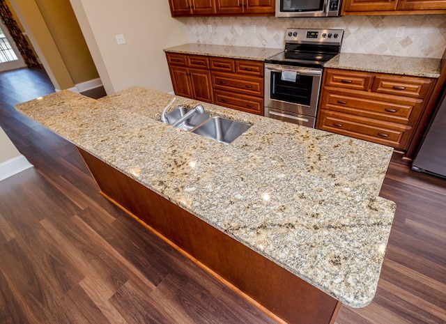 kitchen with light stone countertops, sink, tasteful backsplash, dark hardwood / wood-style floors, and appliances with stainless steel finishes