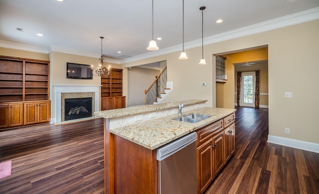 kitchen with built in shelves, decorative light fixtures, stainless steel dishwasher, and an island with sink