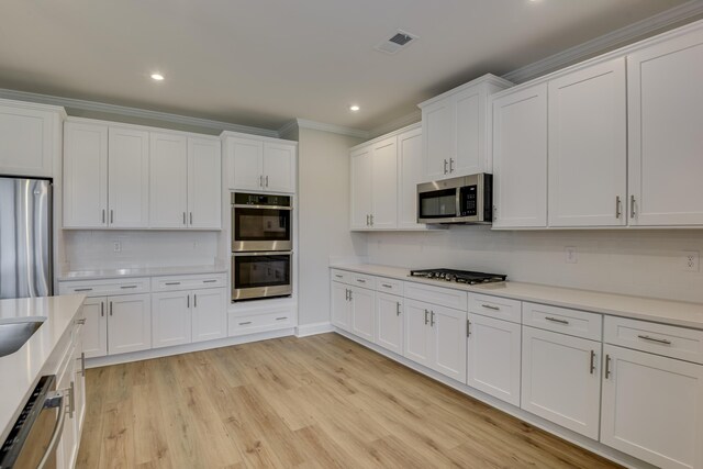 kitchen featuring visible vents, light countertops, ornamental molding, appliances with stainless steel finishes, and white cabinets