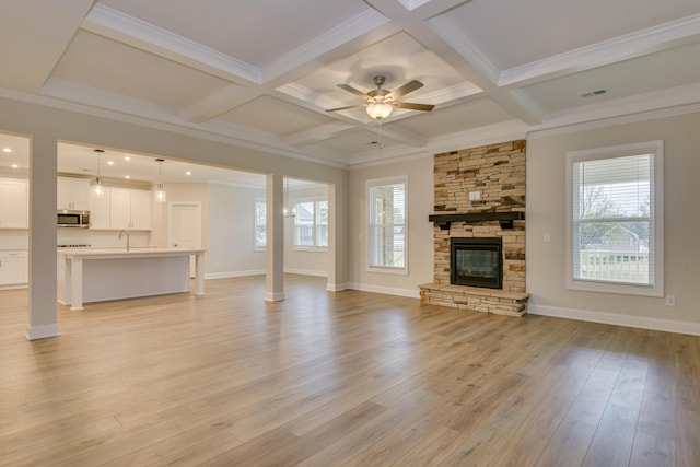 unfurnished living room with plenty of natural light, visible vents, coffered ceiling, and light wood-style floors