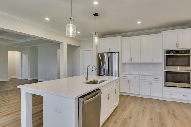 kitchen featuring light countertops, ornamental molding, light wood-style flooring, appliances with stainless steel finishes, and a sink