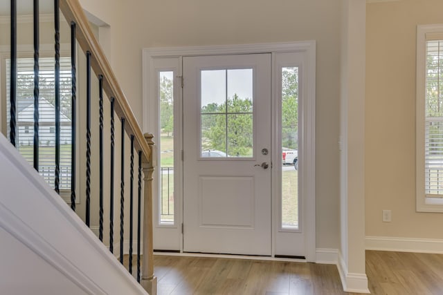 foyer with stairway, a wealth of natural light, baseboards, and light wood finished floors