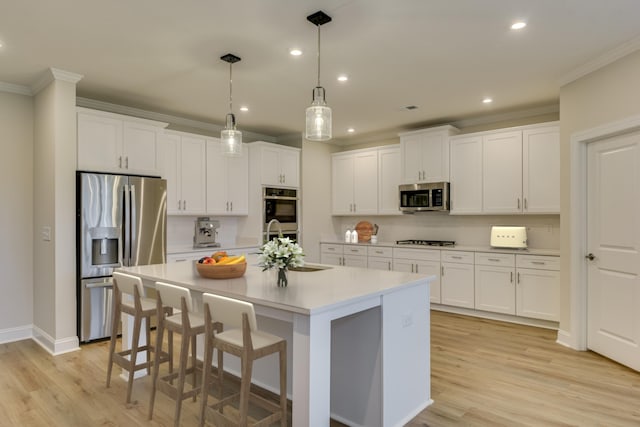 kitchen with crown molding, light wood-style flooring, light countertops, and appliances with stainless steel finishes