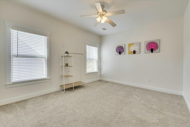 carpeted empty room featuring a ceiling fan, visible vents, and baseboards