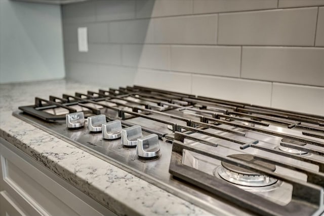 room details with light stone countertops and stainless steel gas stovetop