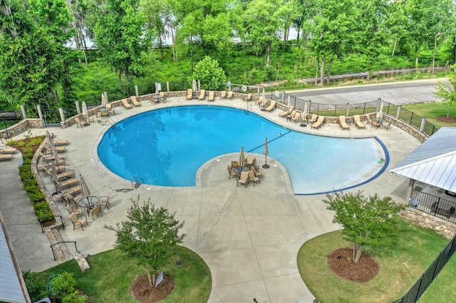 community pool with a patio area and fence