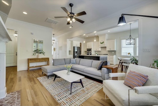 living area with light wood finished floors, visible vents, a ceiling fan, ornamental molding, and recessed lighting