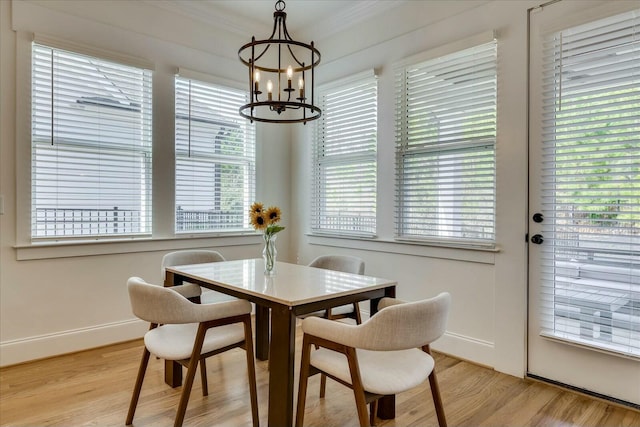 dining room featuring a chandelier, baseboards, light wood-style flooring, and crown molding