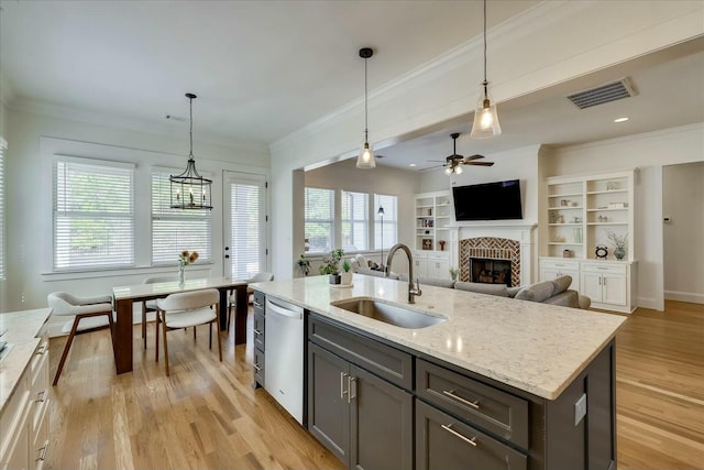 kitchen featuring a sink, visible vents, light wood-type flooring, dishwasher, and crown molding