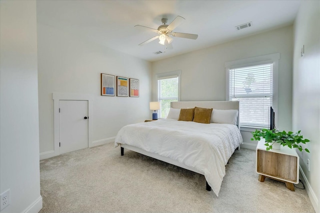 bedroom with baseboards, visible vents, and light colored carpet