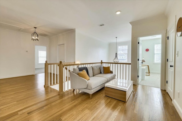 living area featuring visible vents, light wood-style flooring, an upstairs landing, and crown molding