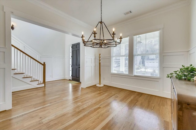 unfurnished dining area featuring visible vents, a decorative wall, stairway, and light wood finished floors