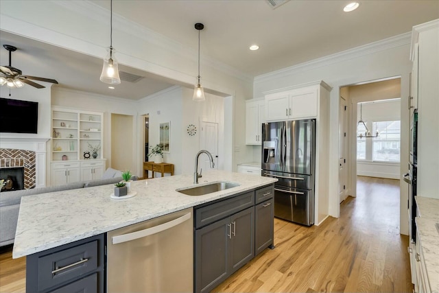 kitchen featuring stainless steel appliances, open floor plan, a sink, and a tiled fireplace