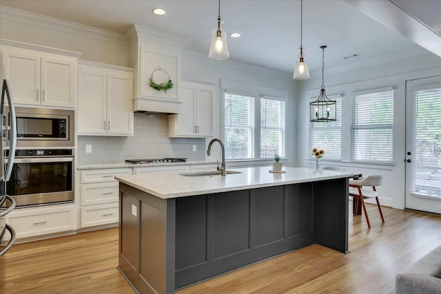 kitchen featuring light wood-style flooring, a sink, white cabinetry, ornamental molding, and appliances with stainless steel finishes