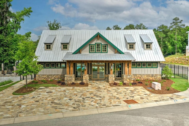 view of front of house featuring stone siding, french doors, board and batten siding, and a standing seam roof