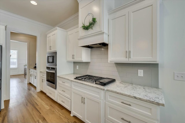 kitchen with crown molding, stainless steel appliances, tasteful backsplash, white cabinetry, and light wood-type flooring