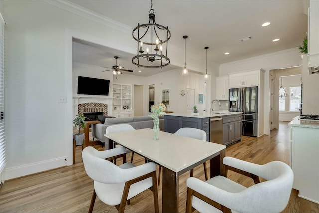 dining space with ornamental molding, light wood-type flooring, built in shelves, a fireplace, and recessed lighting