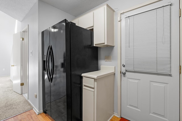 3252 Summerchase Cir, Augusta, GA 30909 - kitchen with black refrigerator with ice dispenser, light wood-type flooring, white cabinetry, light countertops, and a textured ceiling