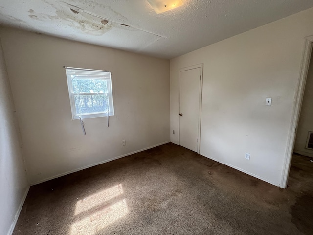 unfurnished room featuring a textured ceiling, carpet, and baseboards