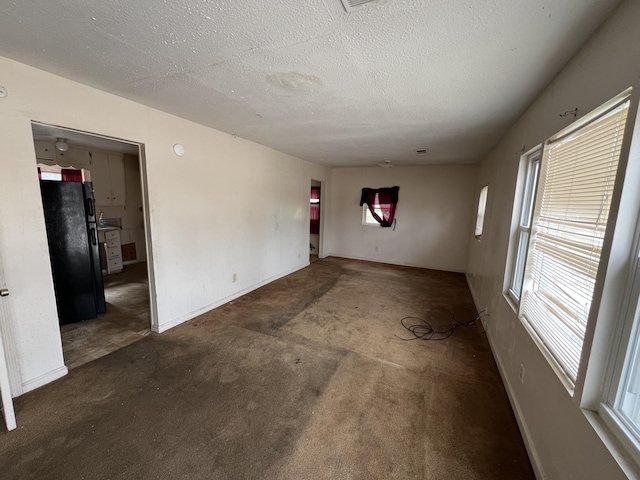 spare room with carpet floors, baseboards, and a textured ceiling