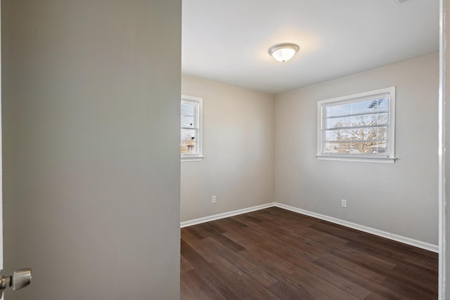 empty room with dark wood-style floors and baseboards