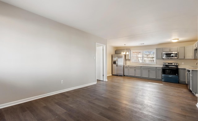 kitchen with baseboards, gray cabinets, stainless steel appliances, light countertops, and pendant lighting