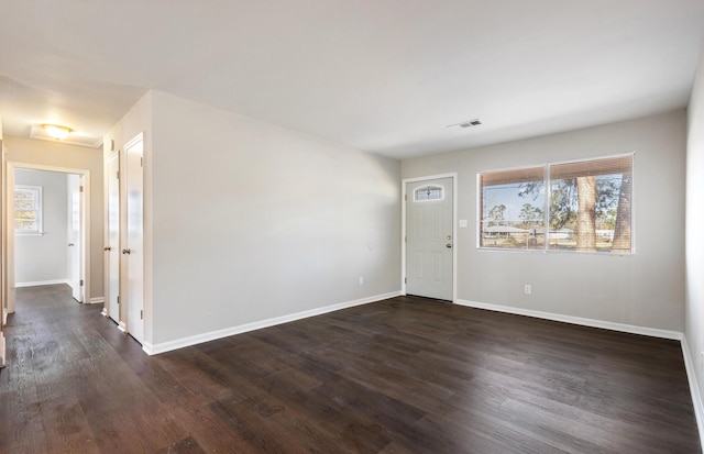 foyer entrance with baseboards, visible vents, and dark wood finished floors