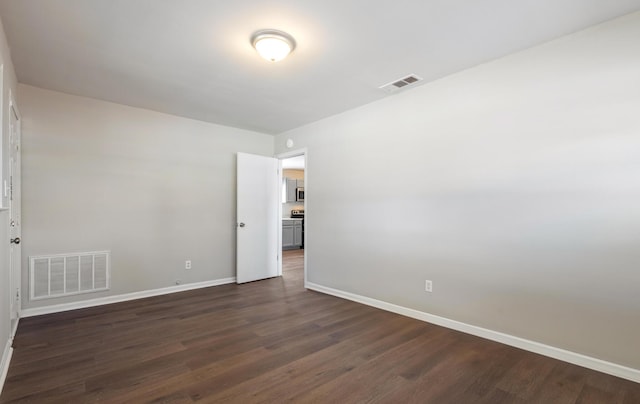 empty room with visible vents, dark wood finished floors, and baseboards