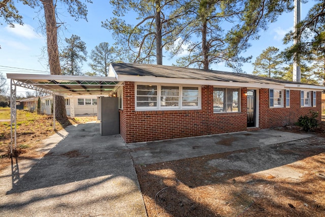 single story home with a carport, concrete driveway, and brick siding