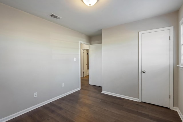 unfurnished bedroom with dark wood-style flooring, visible vents, and baseboards