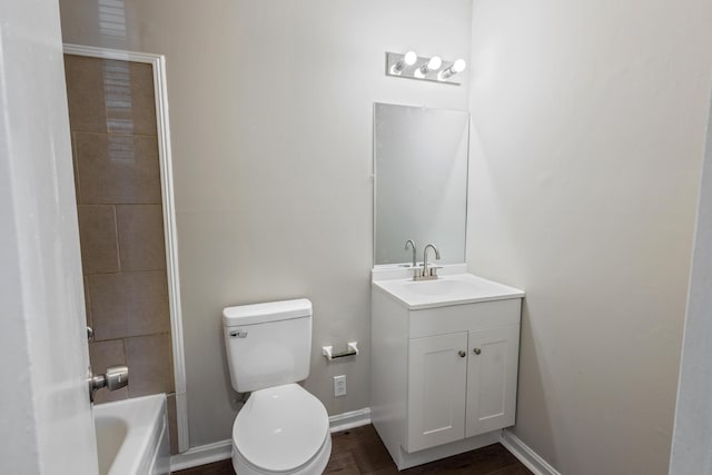 full bathroom with toilet, a bathing tub, baseboards, and vanity