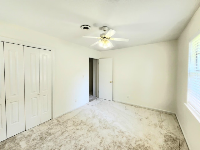 unfurnished bedroom with ceiling fan, light colored carpet, and a closet