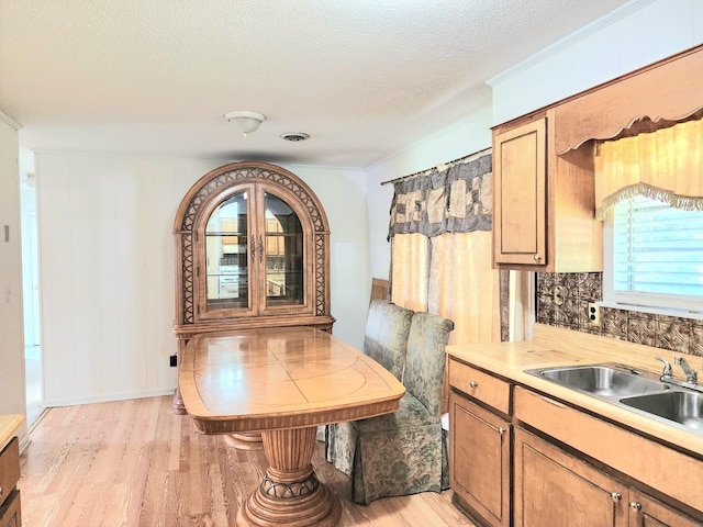 dining room with light wood-type flooring, a textured ceiling, and sink