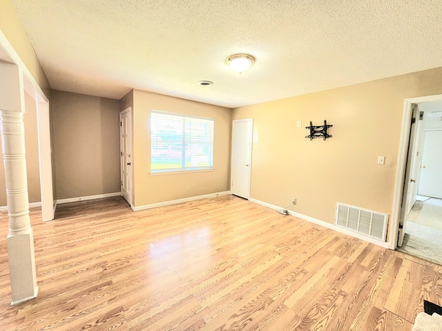 spare room with a textured ceiling and light hardwood / wood-style flooring