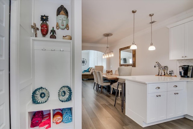 kitchen featuring backsplash, white cabinetry, crown molding, and hanging light fixtures