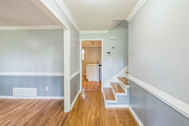 4572 Colonial Rd, Martinez, GA 30907 - hall featuring light wood-type flooring, a textured ceiling, baseboards, stairway, and crown molding